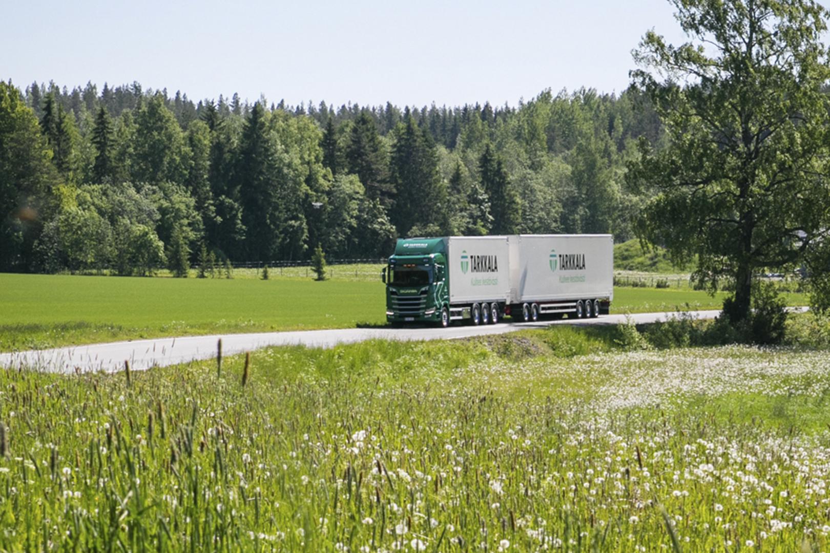 Tarkkalan auto ajaa kesäisessä maisemassa